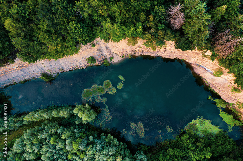 Blue lake at an old quarry surrounded by green forest 