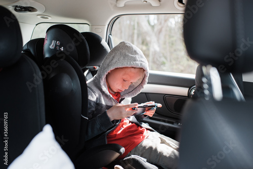 boy sat in his car seat playing a Nintendo video game console photo