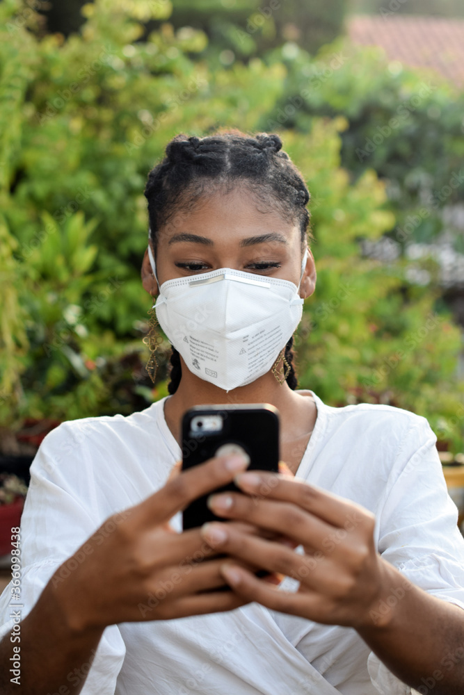 Young black woman in face mask using a smartphone Young black woman in face mask using a smartphone