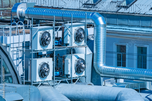 Air conditioners on roof of building Several air conditioners next to ventilation pipes. Roof air purification system. Engineering communications. Room ventilation. Concept - sale of conditioners.