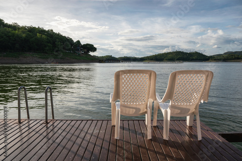 Two chair on deck floating in lake at evening