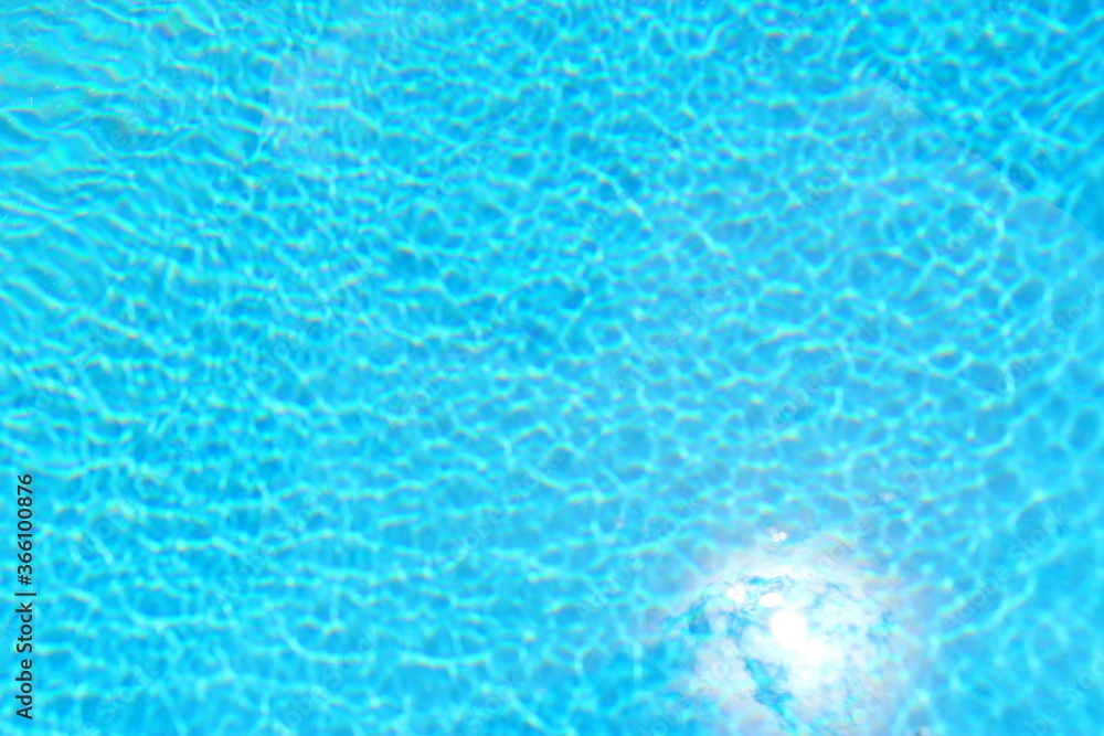 Blue water in the pool in summer. Relaxation and rest. The sun's rays are reflected in the water.