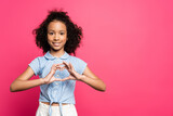 smiling cute curly african american kid showing heart with hands isolated on pink