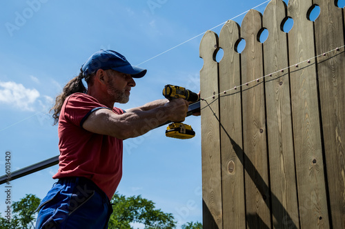 A man builds a wooden fence.