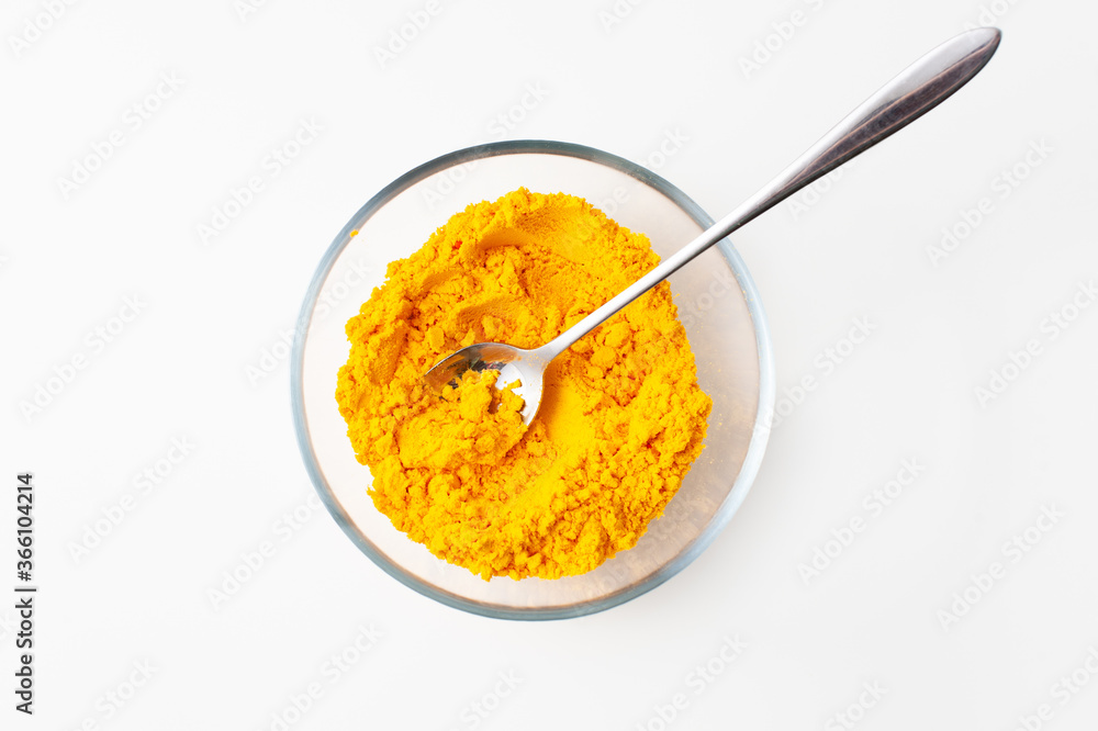 Spoon with turmeric spices in a bowl on a white background. Spoon with turmeric spices in a bowl on a white background.