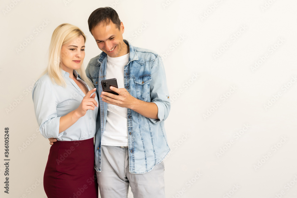 Beautiful, pretty, cute woman and handsome man in shirts writing sms through 3g internet on smart phones over grey background