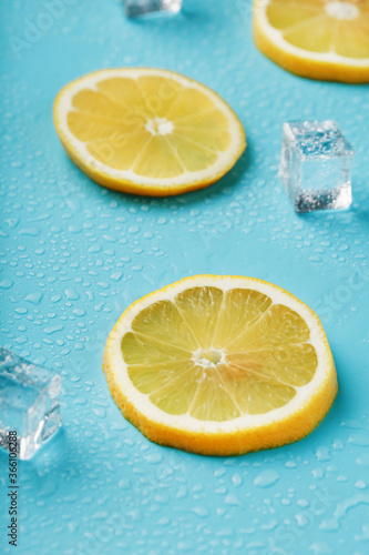 Slices of fresh lemon on a blue background with ice.