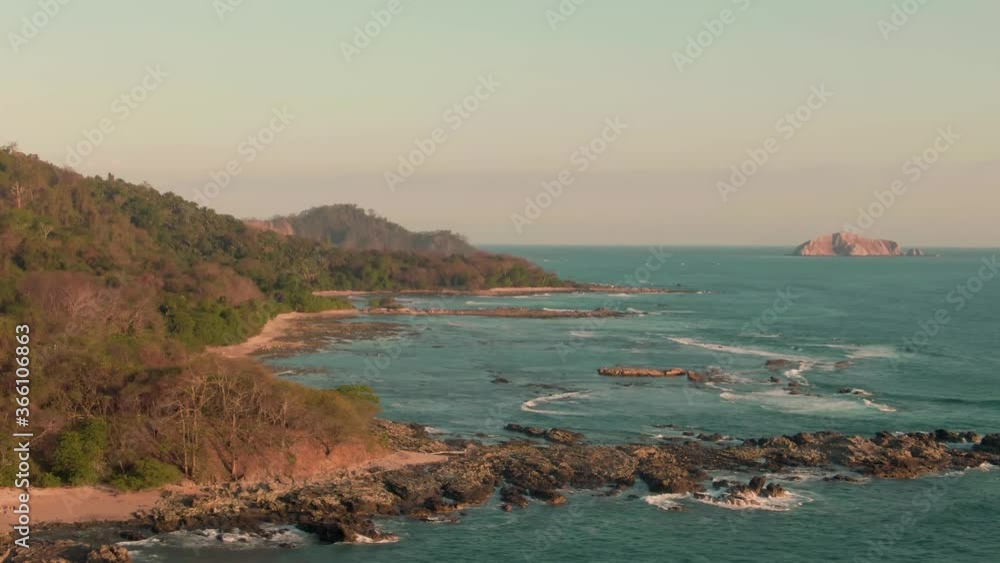 Aerial parallax view of tide swell breaking on Costa Rica beach in warm sunlight