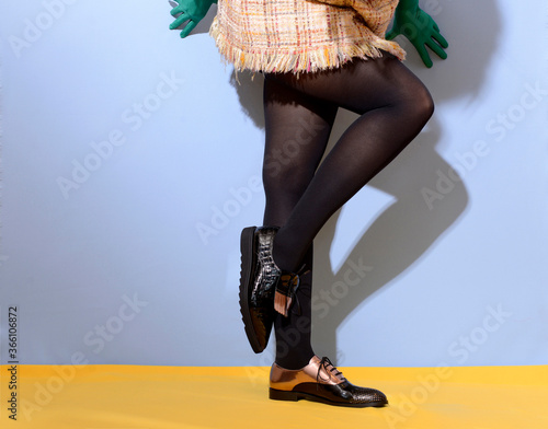 Photographie Girl legs in black stockings and different monk shoes and green gloves over isol