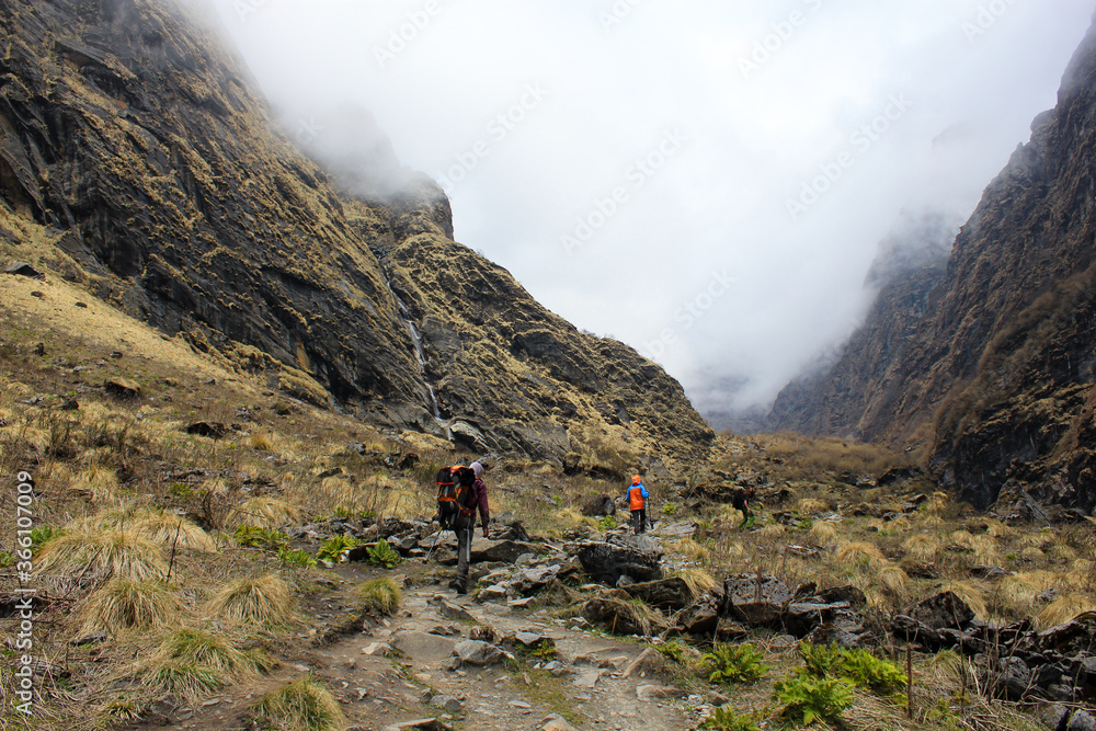 Trekkers with a guide traversing a valley on the Himalayan Annapurna Base Camp trek route