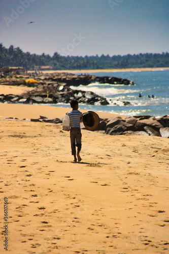 little poor boy with hat and bag on the beach