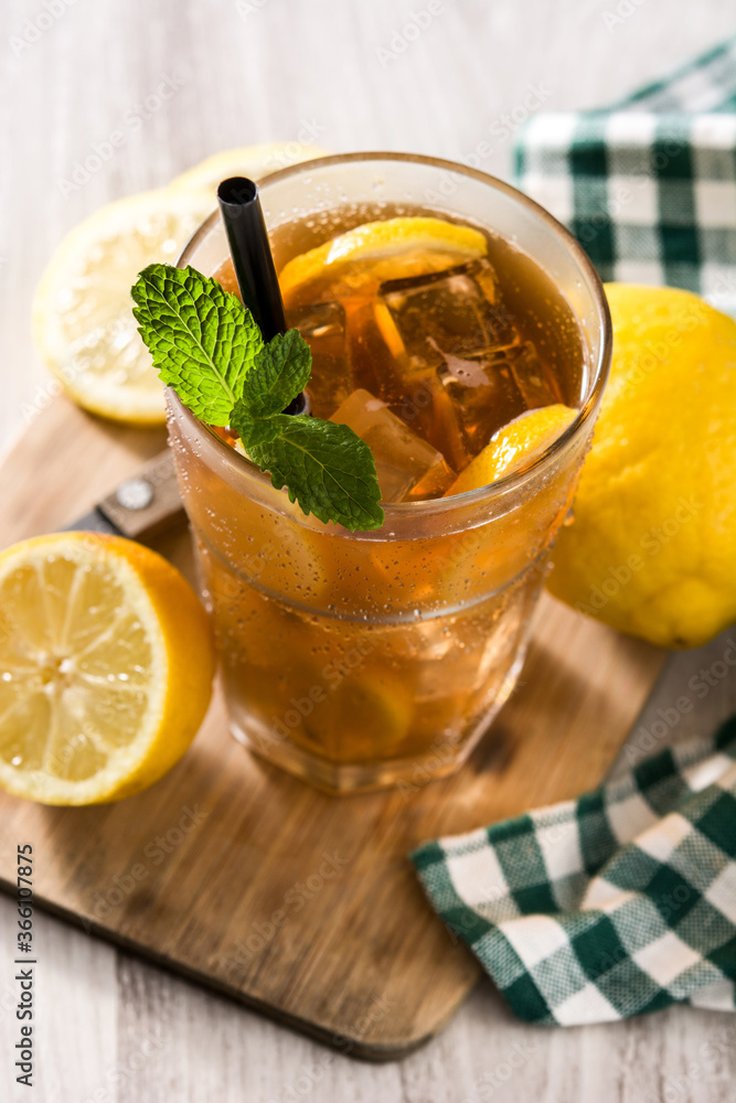 Iced tea drink with lemon in glass and ice on white wooden table