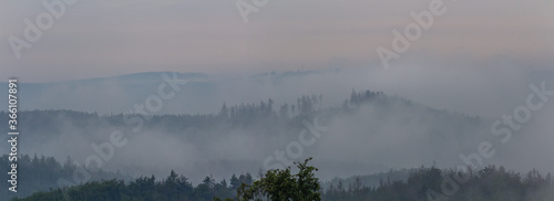 Panoramic view to forest silhouette with misty fog. Czech landscape