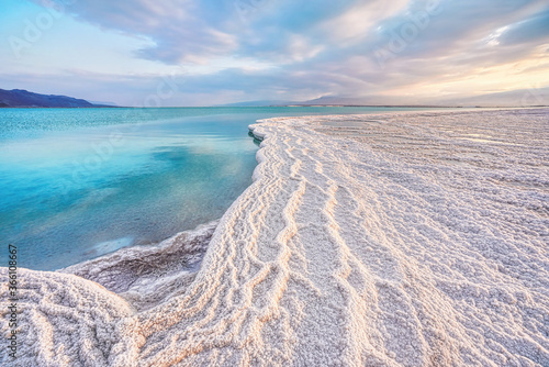 Morning sun shines on salt crystals formations  clear cyan green calm water near  typical landscape at Ein Bokek beach  Israel