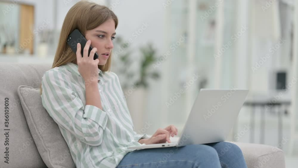 Young Woman with Laptop Talking on Smartphone at Home Young Woman with Laptop Talking on Smartphone at Home