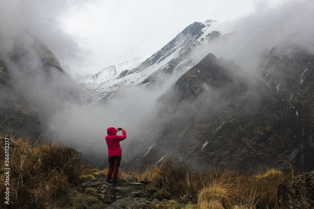 Trekker is taking a photo of clouded Machapuchare (Fishtail) in Himalayan mountains