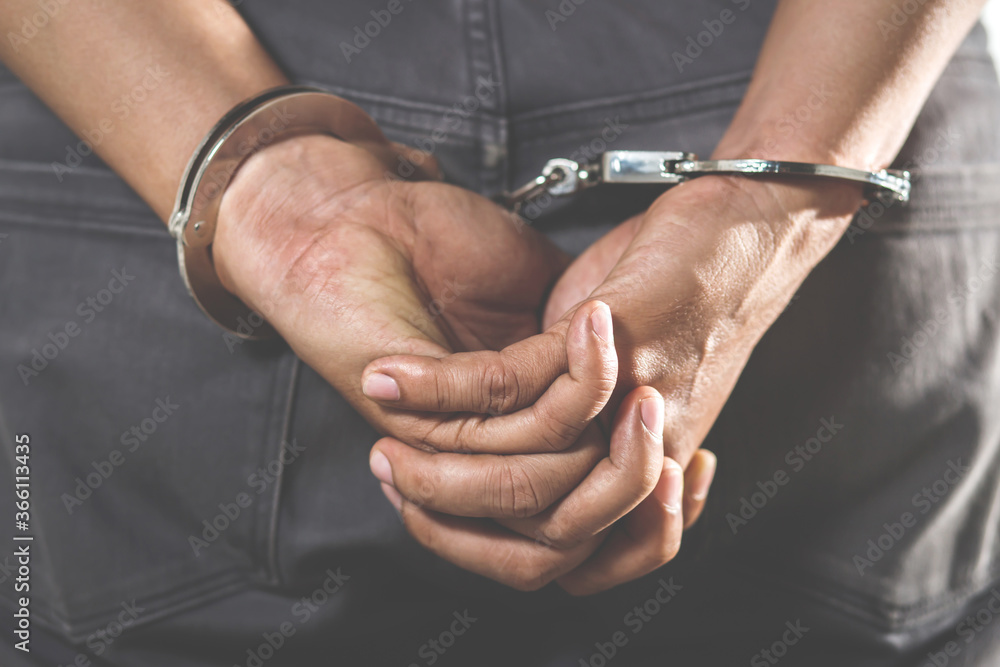 Prisoner male criminal standing in handcuffs with hands behind back. 