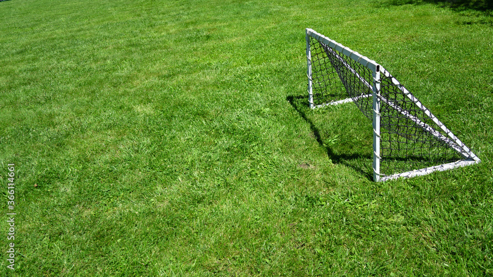 View of freestanding mini soccer goal post net on outdoor football green grass field copy space