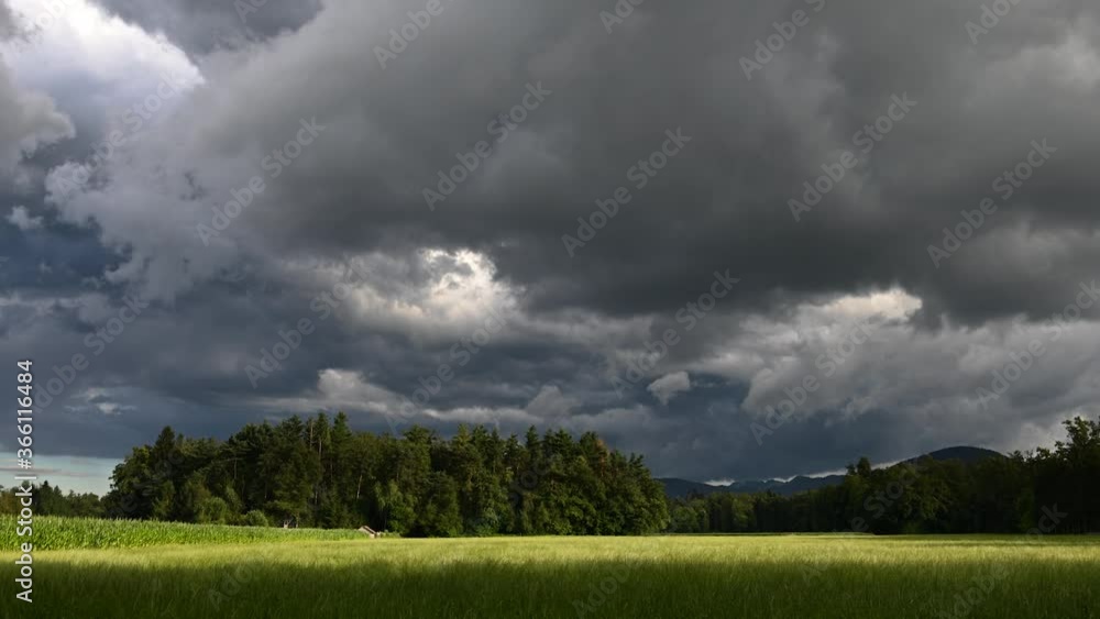 Time lapse of summer storm dramatic clouds forming over farming field meadow and forest trees. Slow zoom in Time lapse of summer storm dramatic clouds forming over farming field meadow and forest trees. Slow zoom in