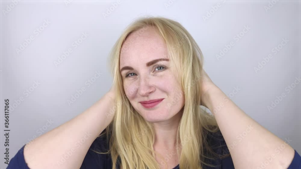 Natural blonde tosses and fluffs her hair in front of the camera. The concept of proper hair care. Slow motion Natural blonde tosses and fluffs her hair in front of the camera. The concept of proper hair care. Slow motion
