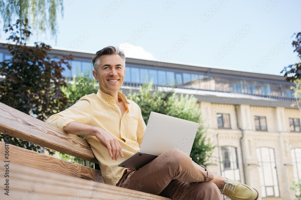 Handsome mature businessman using laptop computer, planning start up, sitting outdoors. Smiling confident freelancer working in park, sitting on bench. Successful business concept Handsome mature businessman using laptop computer, planning start up, sitting outdoors. Smiling confident freelancer working in park, sitting on bench. Successful business concept