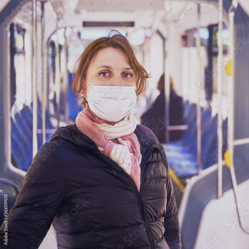 Red-haired woman on public transport, close-up portrait in a medical mask