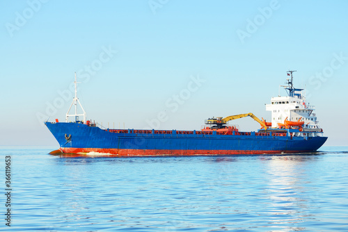 Large blue bulk carrier (ship) sailing in the Baltic sea to Riga port, Latvia. A view from the yacht. Global communications, logistics, industry, freight transportation photo