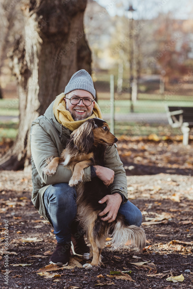 Portrait of smiling man embracing dog while crouching at park during autumn Portrait of smiling man embracing dog while crouching at park during autumn