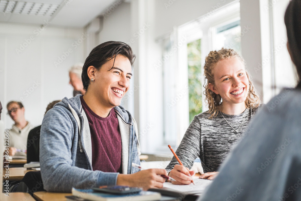 Smiling young man with female friend in classroom Smiling young man with female friend in classroom