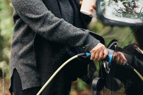 Midsection of mid adult woman charging electric car photo