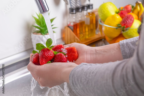 Woman washing strawberries in the kitchen