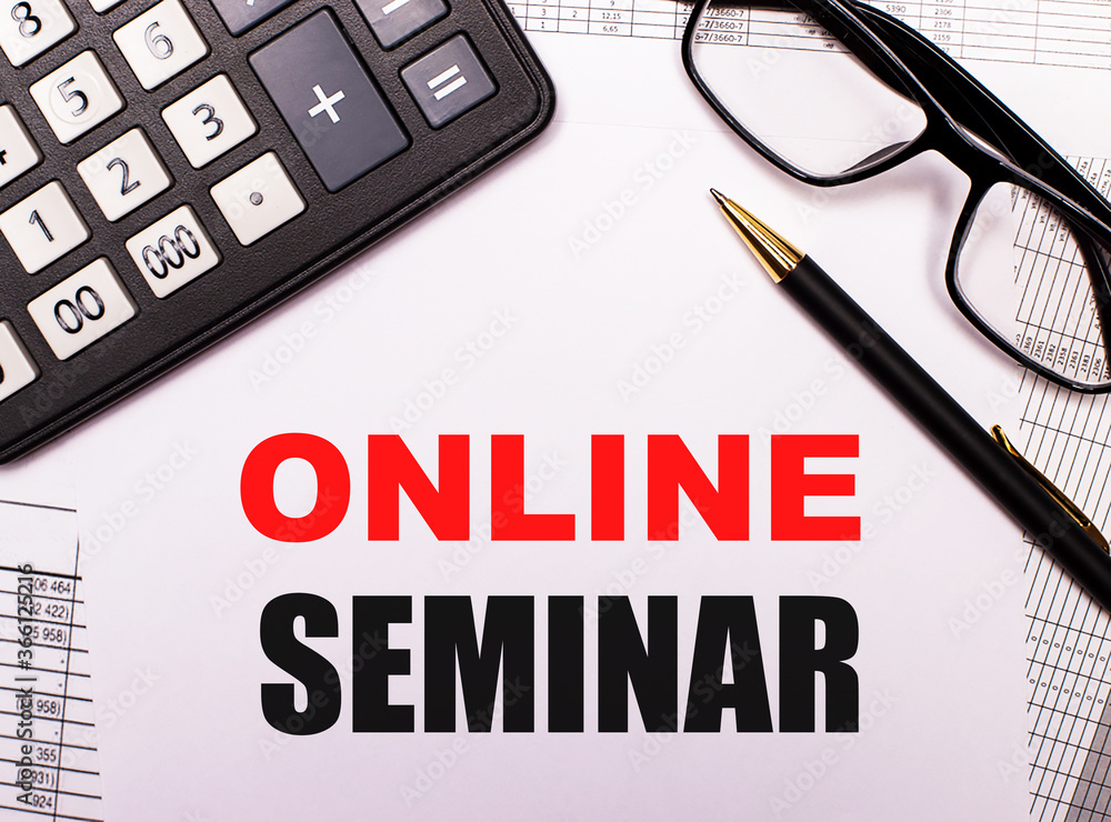 Fototapeta premium ONLINE SEMINAR written on a light sheet next to a calculator, black-framed glasses and a pen. Internet concept