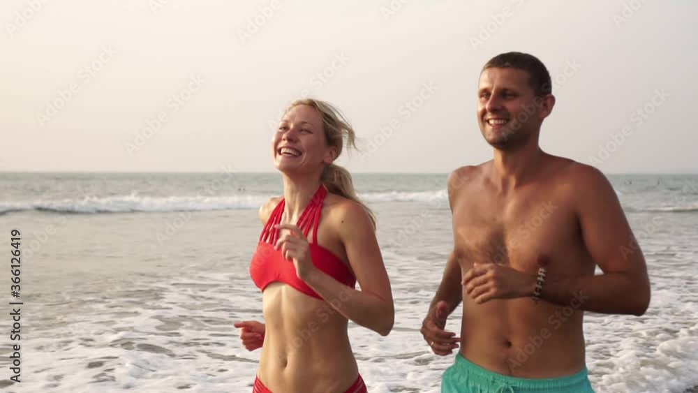 Young beautiful couple man and woman jogging on the sea beach Young beautiful couple man and woman jogging on the sea beach