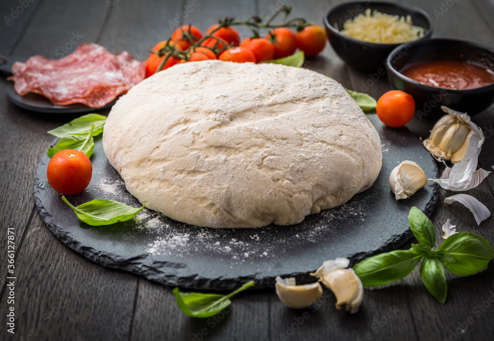 Fresh raw dough for pizza with ingredients and spices on wooden table Fresh raw dough for pizza with ingredients and spices on wooden table