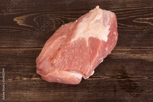 A large piece of fresh raw pork meat on the kitchen table, before cooking it