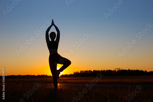 Fototapeta Naklejka Na Ścianę i Meble -  young woman doing yoga at sunset in summer