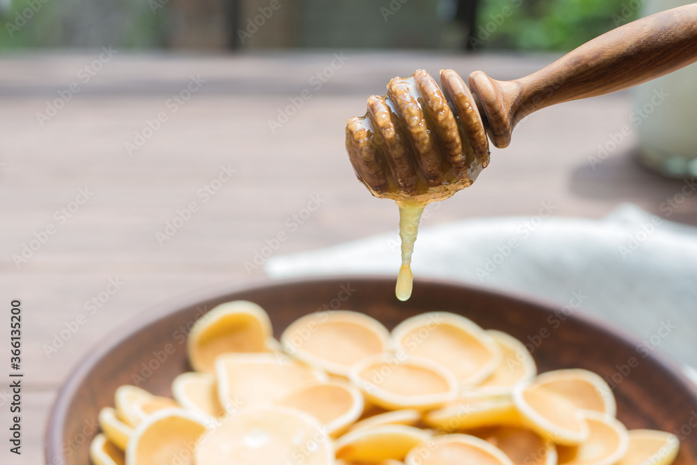 Wooden spoon for honey close-up. Drops of honey flow down on traditional american breakfast cereal mini Pancakes. Wooden spoon for honey close-up. Drops of honey flow down on traditional american breakfast cereal mini Pancakes.