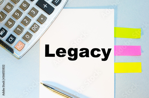 The text legacy is written on a notebook on a blue background with a calculator and pen.