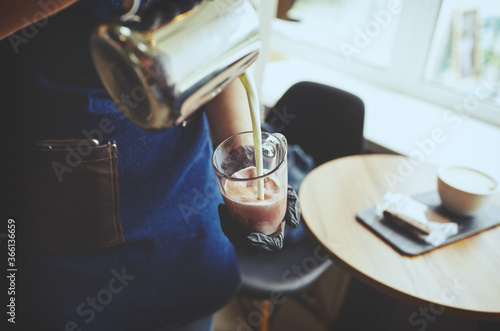 Barista making pink matcha latte with milk. Bartender preparing tasty drink.Blurred image,selective focus