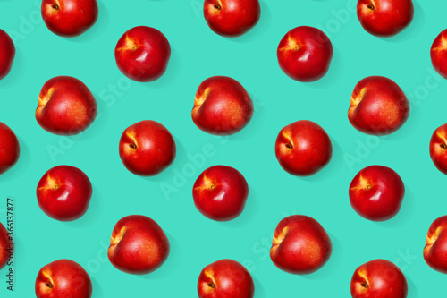 Juicy, bright nectarines on an emerald background. Tasty and healthy snack. Many vitamins in fruits. Background pattern.