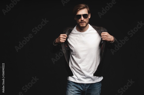 Fashion man, Handsome serious beauty male model portrait wear sunglasses and leather jacket, young guy over black background