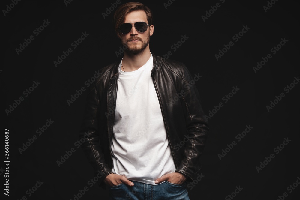 © opolja - Fashion man, Handsome serious beauty male model portrait wear sunglasses and leather jacket, young guy over black background
