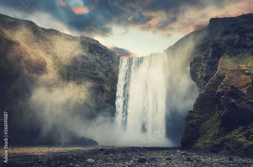Dramatic Icelandic Landscape. Classic long exposure view of famous Skogafoss waterfall with morning fog. Amazing Scenery of Iceland during sunset. Iceland the country of best Incredible nature plases.