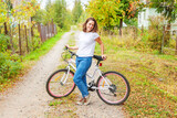Young woman riding bicycle in summer city park outdoors. Active people. Hipster girl relax and rider bike. Cycling to work at summer day. Bicycle and ecology lifestyle concept.