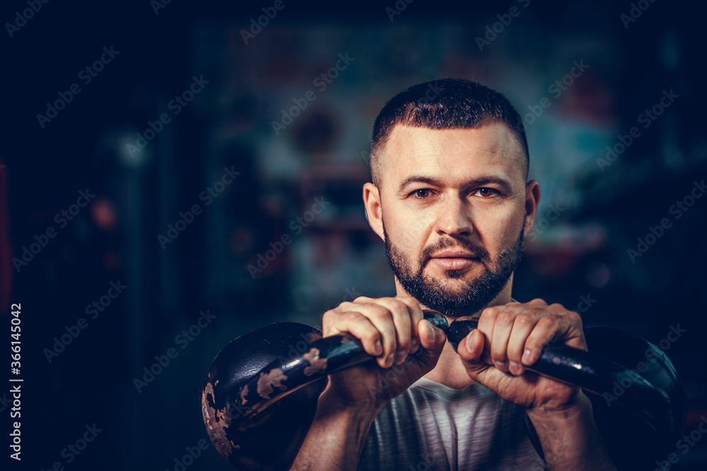 Bearded fitness man doing a weight training by lifting heavy kettlebell. Yong athlete doing kettlebell swings. Bodybuilder lifting with kettlebell. Bearded fitness man doing a weight training by lifting heavy kettlebell. Yong athlete doing kettlebell swings. Bodybuilder lifting with kettlebell.