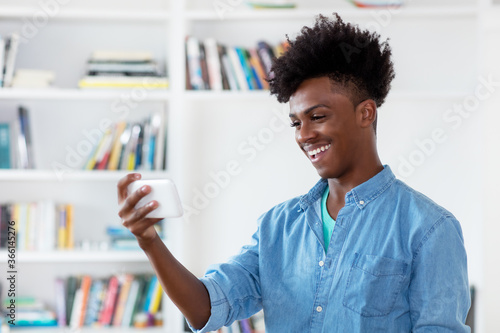 African american young adult man watching video online with mobile phone