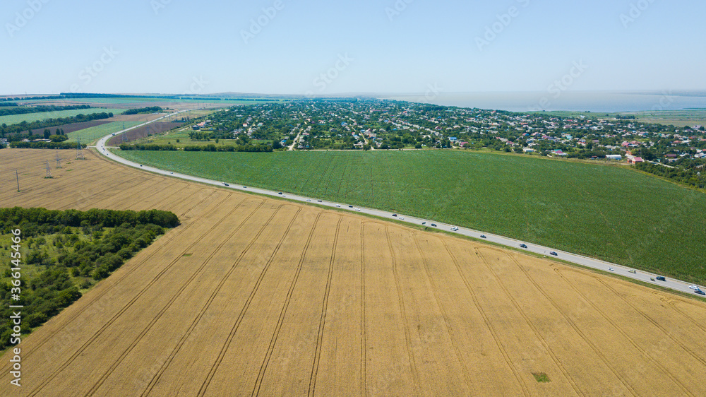 Aerial view of empty highway road between meadow and agricultural field.