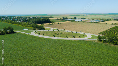 Aerial view of highway traffic circle between meadow and agricultural field.