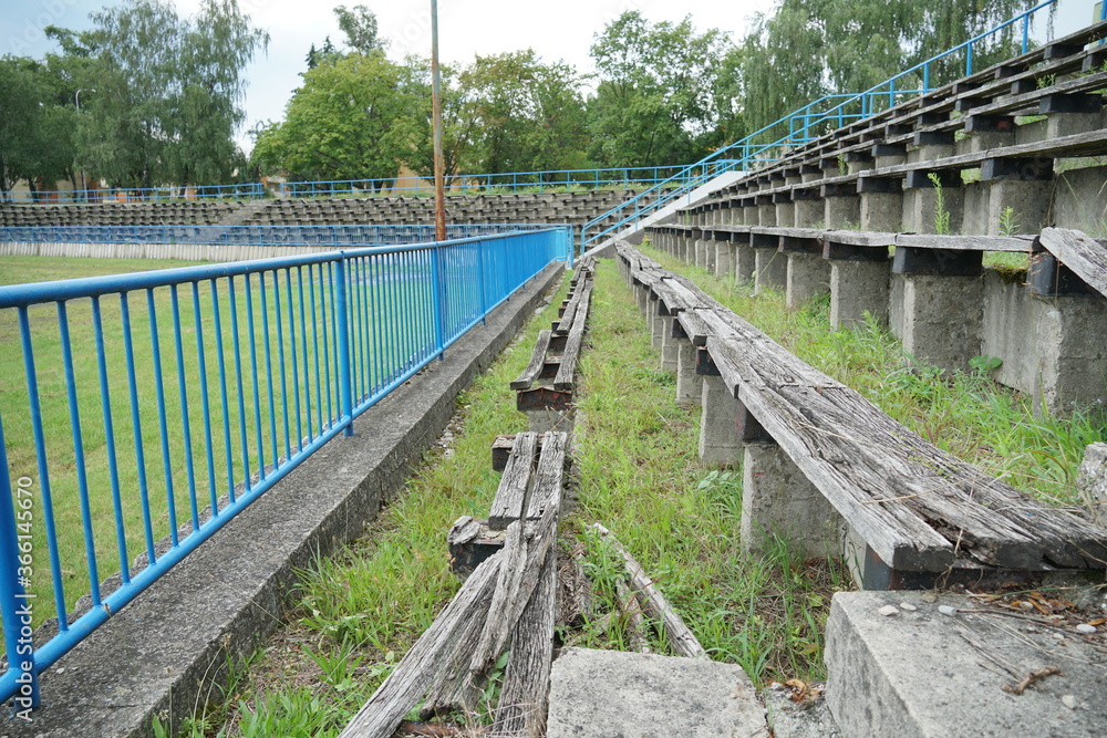 Decayed wooden banks in tribune or auditorium of a devastated football stadium in a provincial town in Eastern Europe.