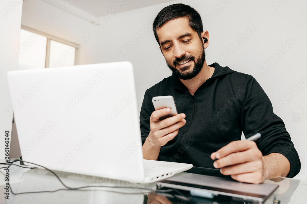 Designer working from home using laptop and tablet. Checking something on the phone Designer working from home using laptop and tablet. Checking something on the phone